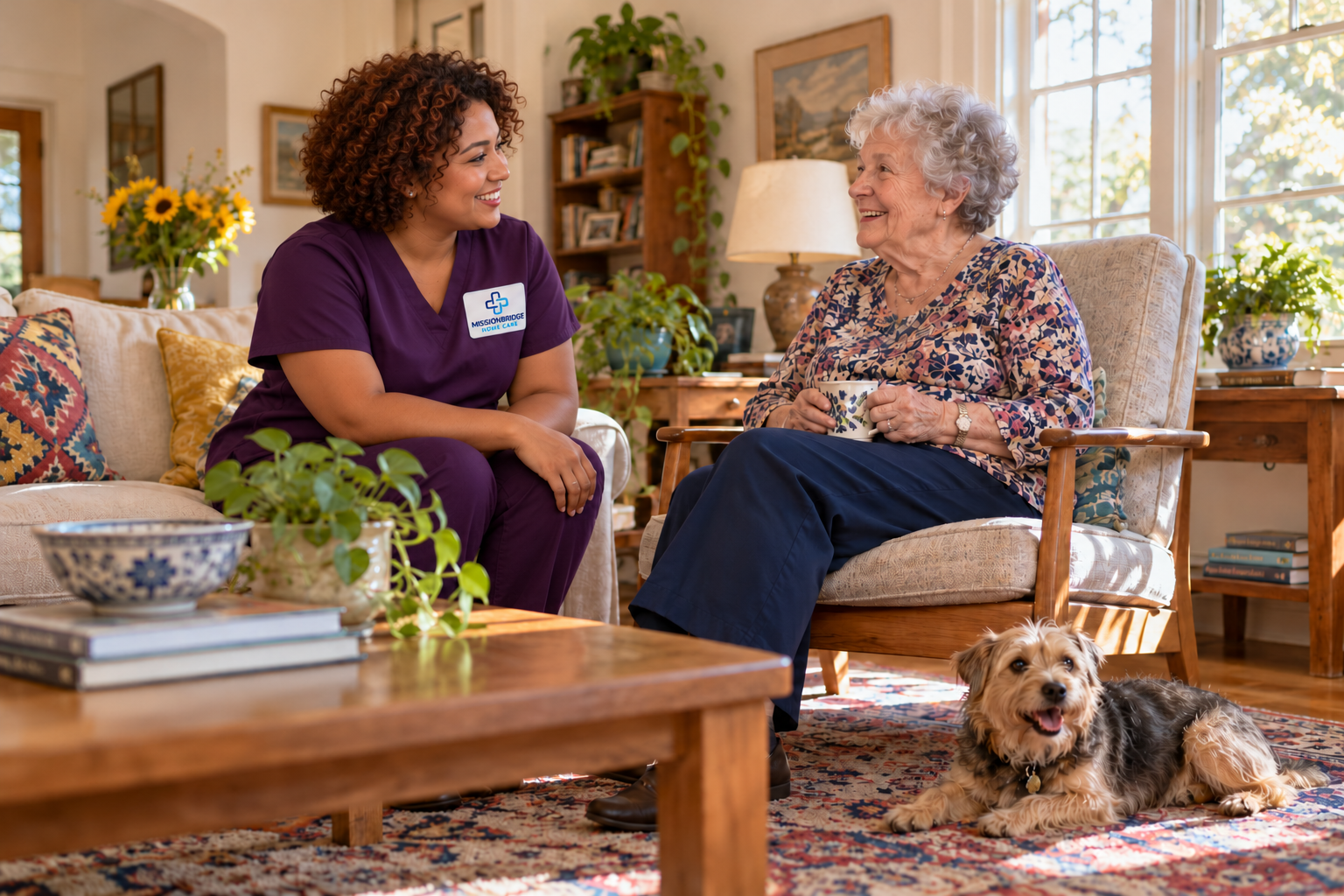 Illustrative companion in branded plum scrubs chatting with an older woman while a terrier rests nearby
