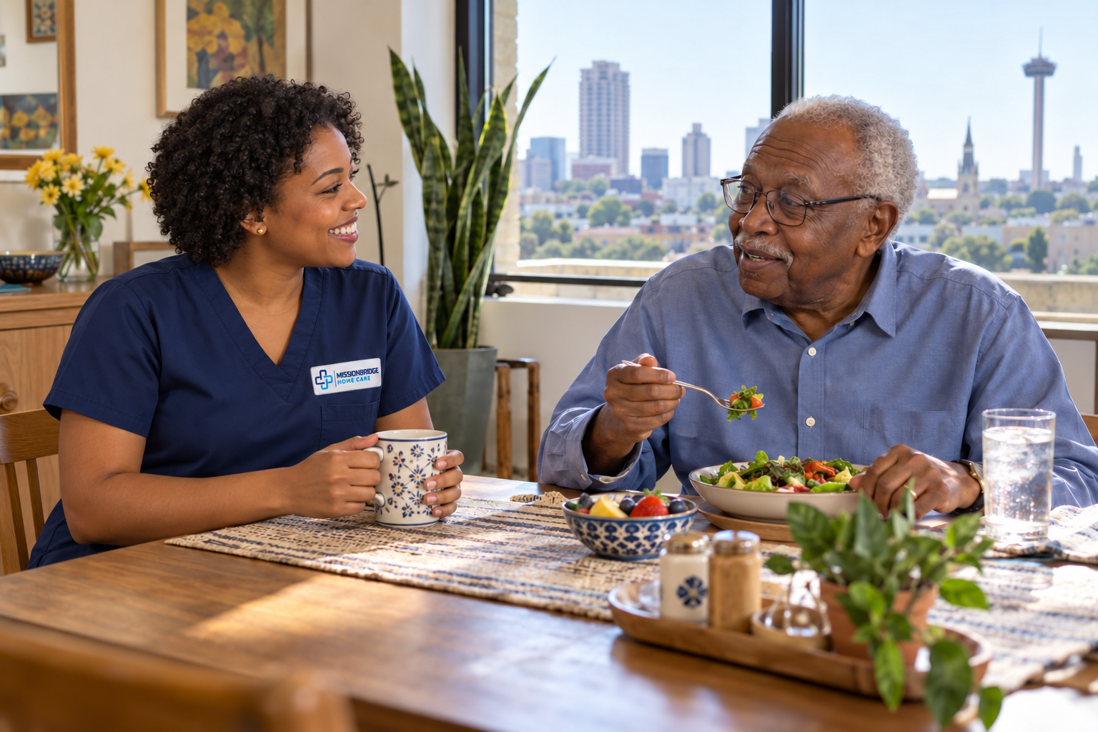 Illustrative Black companion in branded navy scrubs chatting with an older man eating independently